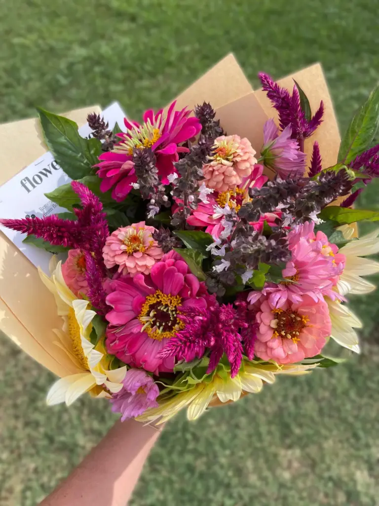 A vivid hand-tied mix of zinnias, cosmos, celosia and sunflowers